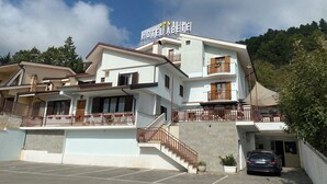 A multi-story hotel with a balcony, a staircase, and a parking area. - BikeHotel Abete (San Giovanni Rotondo)