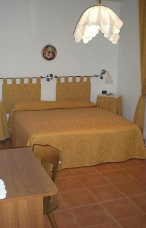 Una habitación con dos camas, una mesa, una lámpara y un cuadro colgado en la pared.