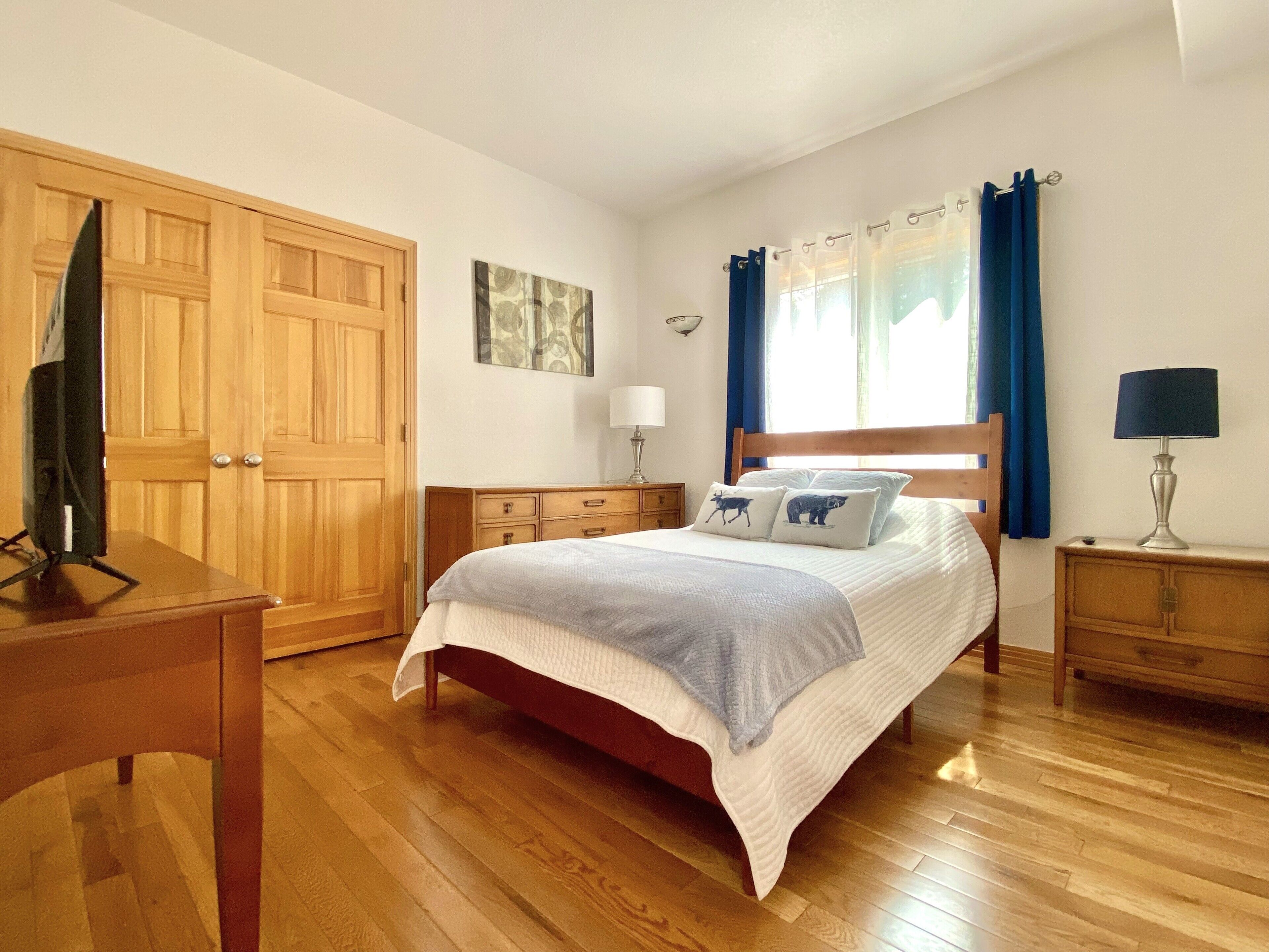 Ein Schlafzimmer mit einem hölzernen Bett, einem Schreibtisch, einem Kleiderschrank und einem Nachttisch.