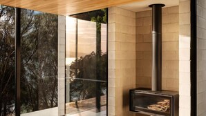 Een modern interieur met een grote glazen wand, een open haard en een leren bank.