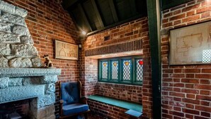 Un coin accueillant avec une cheminée en pierre, un banc et une fenêtre ornée de vitraux.