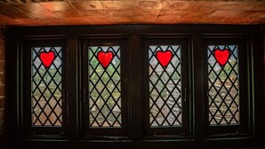 Quatre fenêtres avec des vitres ornées de motifs en losange et de cœurs rouges.