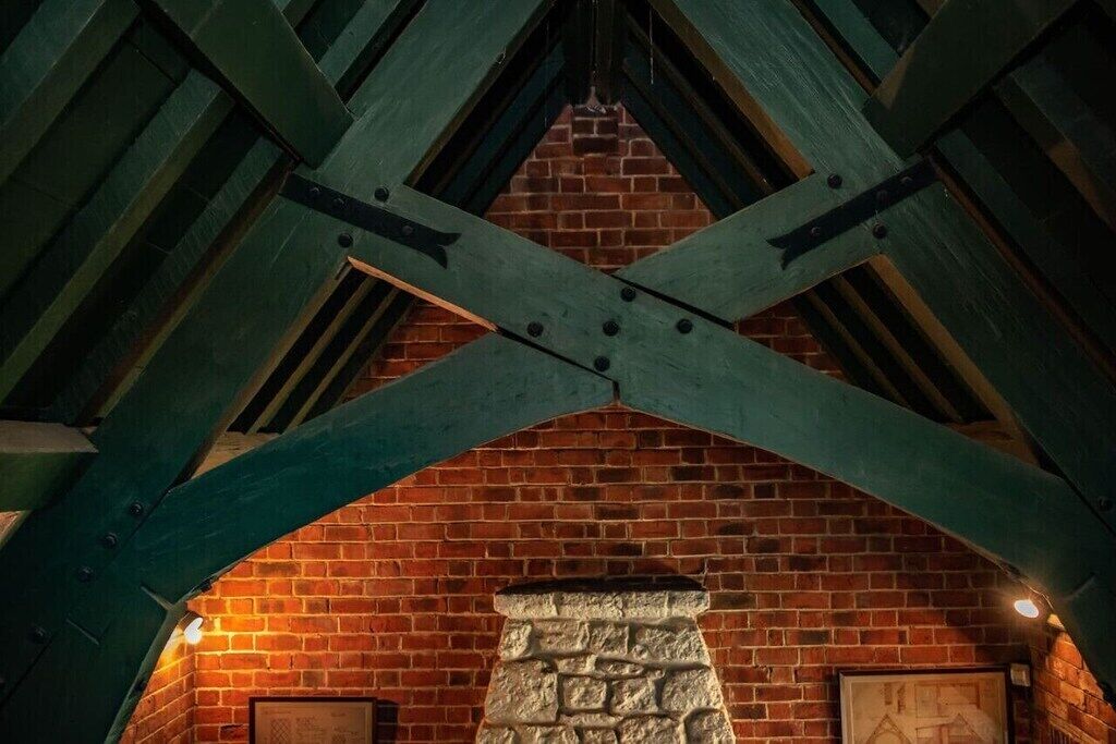 Una chimenea de ladrillo con detalles de piedra, vigas de madera y un cuadro en la pared.