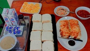 A table with various food items including bread, oranges, and condiments. - Tavua Hotel (Tavua)