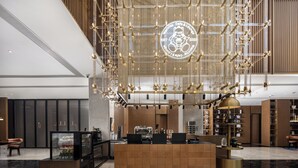 Un interior moderno con una recepción central, una máquina de café y una lámpara decorativa.