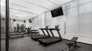 Et moderne fitnesscenter med løbebånd, bænk og spejl.