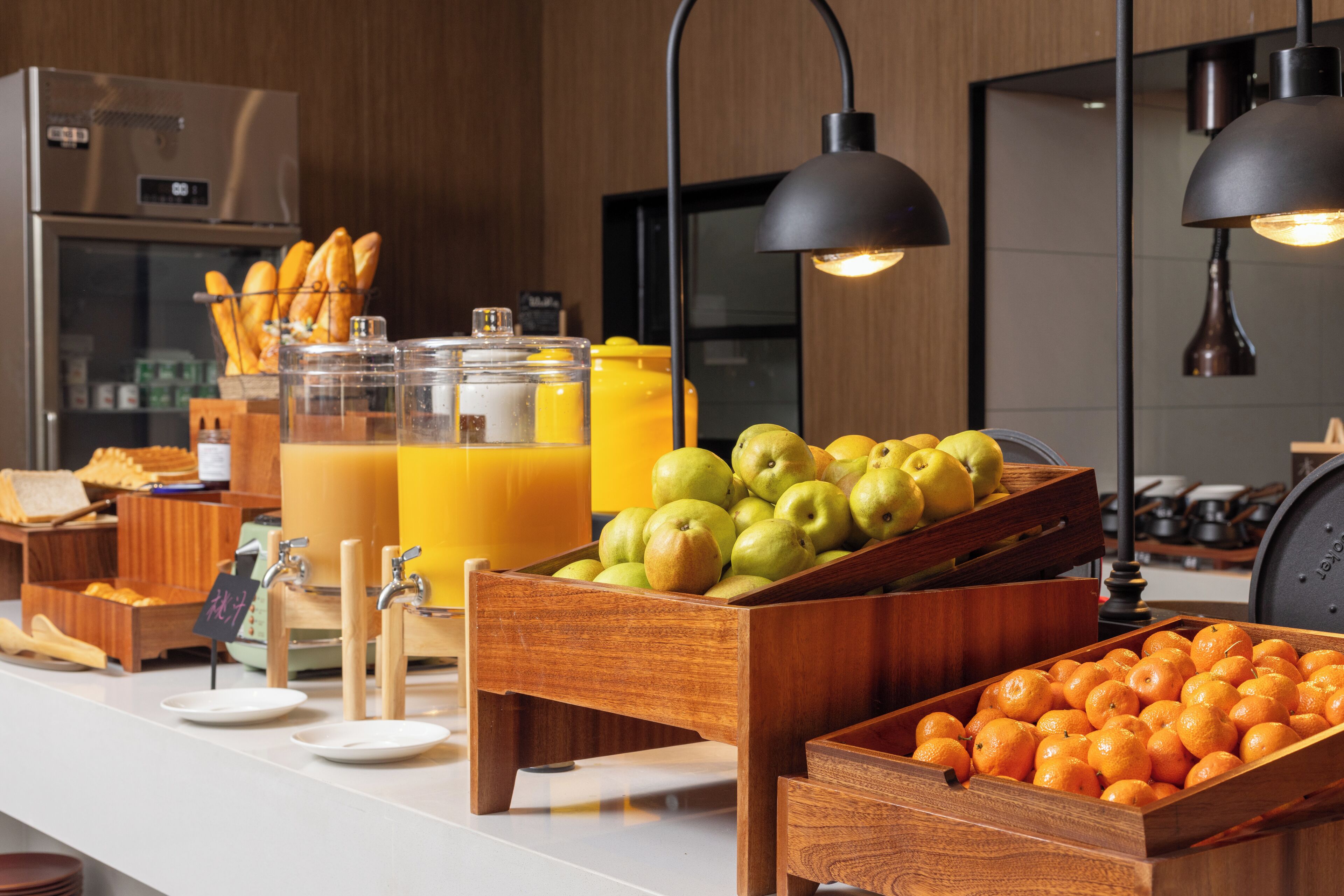 A breakfast buffet with fruits, bread, and juice dispensers.
