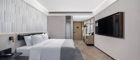 Una habitación de hotel moderna con una cama grande, un televisor de pantalla plana, una mesita de noche y un armario.