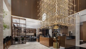 Un moderno vestíbulo de hotel con una zona de bar central, arreglos de asientos y un elemento decorativo de iluminación.