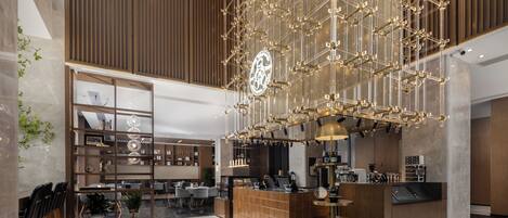 A modern hotel lobby with a central bar area, seating arrangements, and a decorative light fixture.