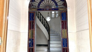 Eine imposante Treppe mit aufwendiger Metallreling und einem dekorativen Oberlicht.