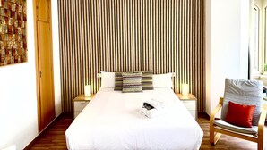Ein modernes Schlafzimmer mit einem großen Bett, einer Wand aus Holzpaneelen und einem Holzstuhl.