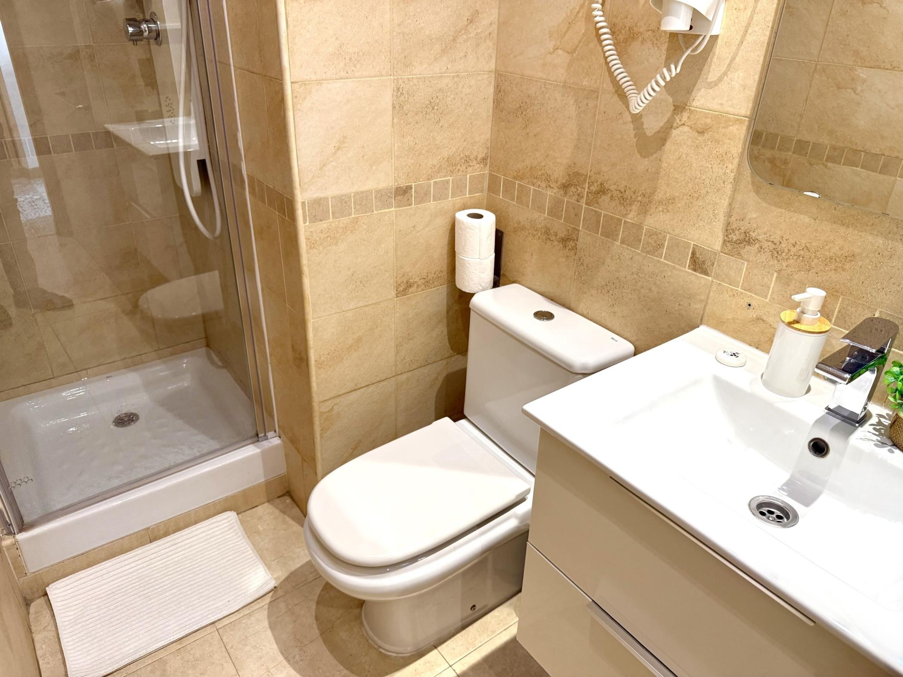 Ein Badezimmer mit Dusche, Toilette und Waschbecken.