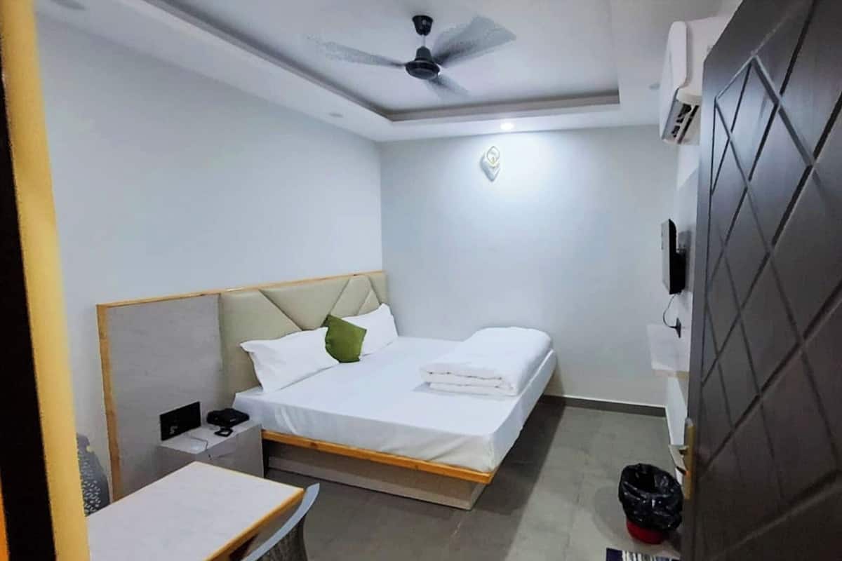 Una habitación de hotel con cama, mesita de noche y ventilador de techo.