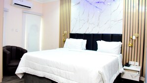 Ein Hotelzimmer mit einem großen Bett, einem Sessel, einem Nachttisch und einer Wand mit marmorartigem Dekor.