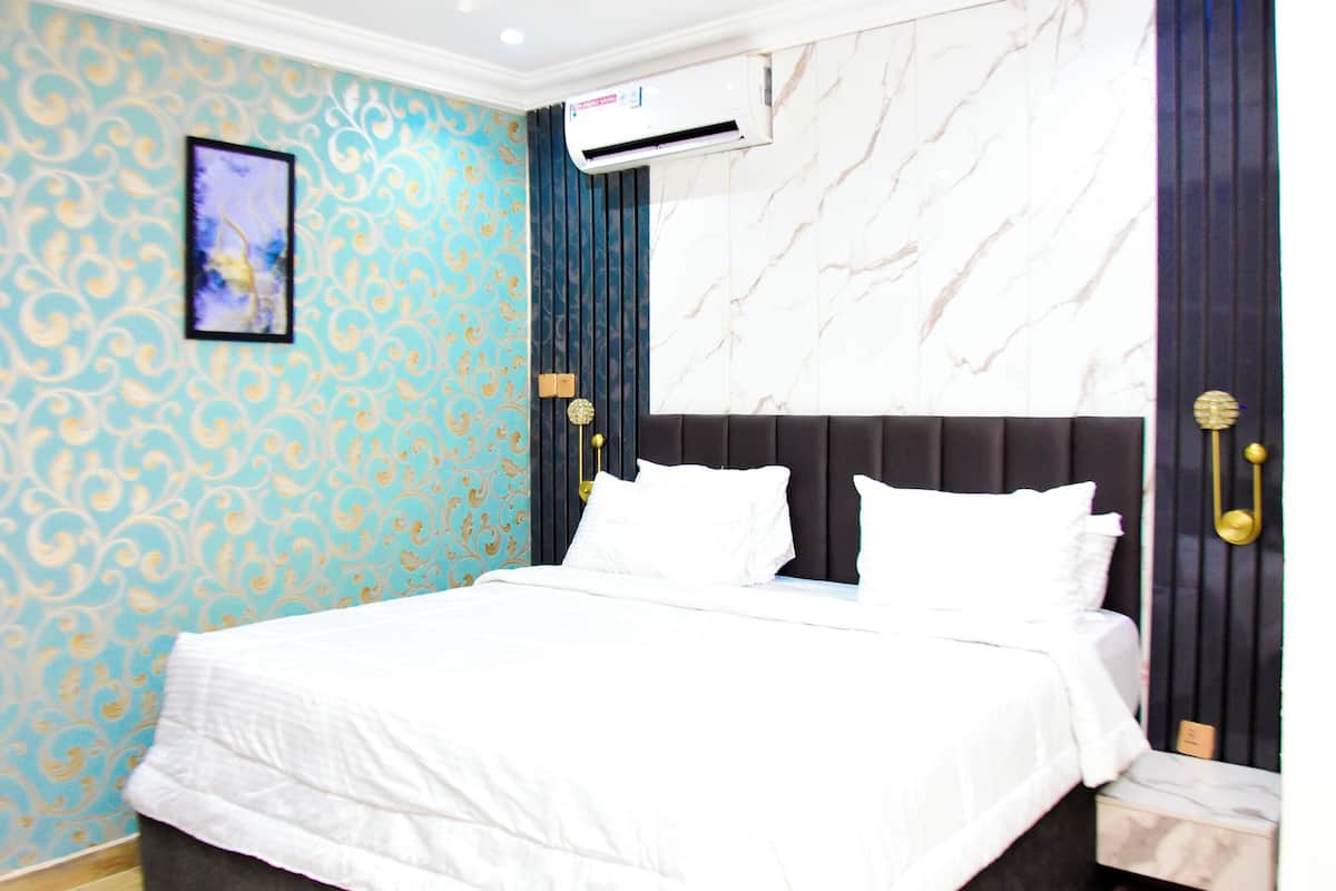 Une chambre à coucher avec un lit, un climatiseur fixé au mur et une tête de lit à motifs de marbre.