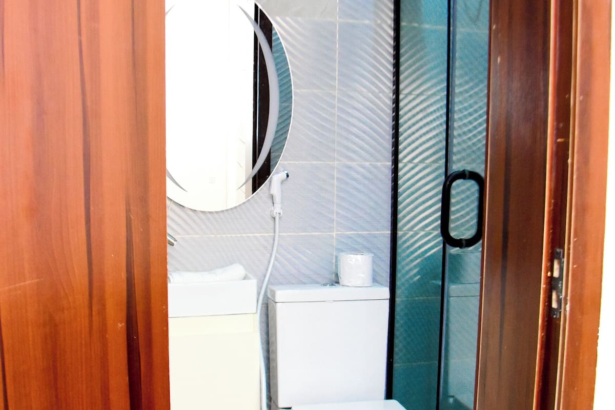 Une salle de bain comprenant des toilettes, un lavabo, un miroir et une douche.