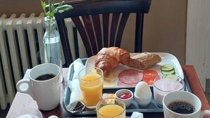 En bakke med morgenmad, blandt andet croissanter, skinke, æg og juice.