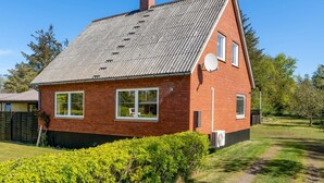 A red brick house with a grey roof, white windows, and a satellite dish.