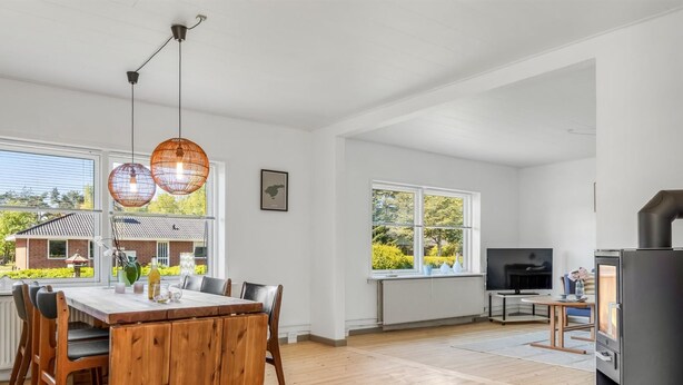 A spacious living area with a wooden dining table, a TV, and a fireplace.