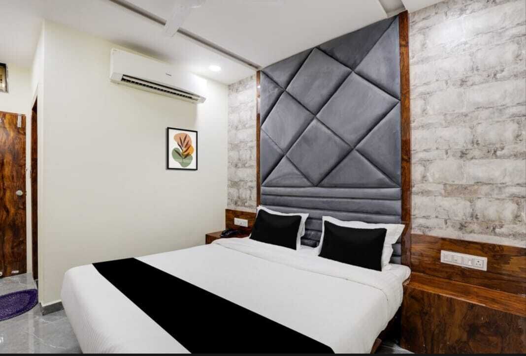 A hotel room with a large bed, a wooden headboard, a marble wall, and a framed picture on the wall.
