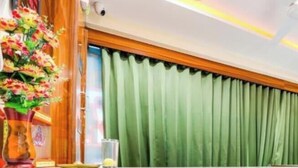 A reception desk with a sign reading "OYO" in a modern hotel lobby with green curtains and a marble counter. - hotel shagun inn  (Ahmedabad)