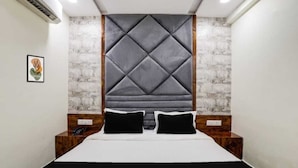 A modern hotel room with a large bed, a headboard with a diamond pattern, wooden nightstands, and a framed picture on the wall. - hotel shagun inn  (Ahmedabad)