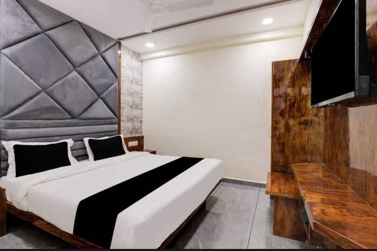 Ein modernes Schlafzimmer mit einem großen Bett, einer hölzernen Bank und einem flachbildfernseher an der Wand.