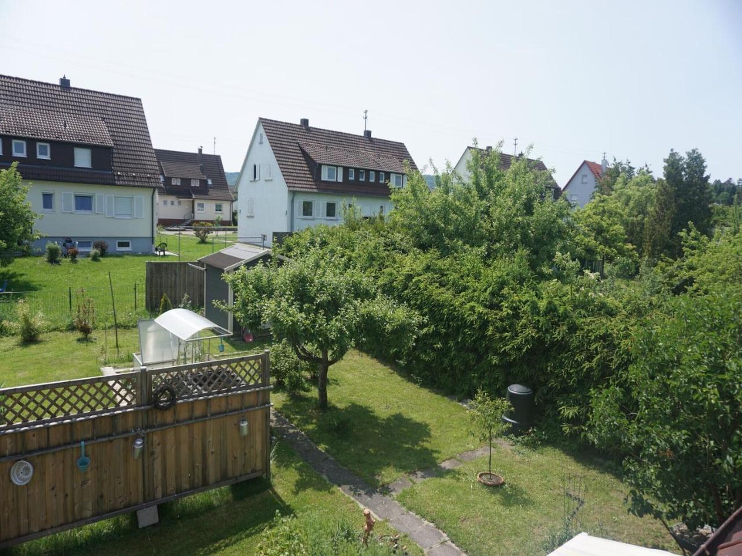 Een woonwijk met huizen, een houten hek, een kleine boom en een voetpad.