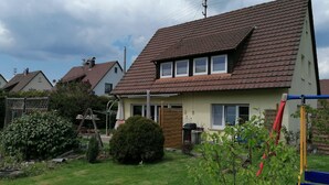 A residential house with a sloped roof, a fenced yard, and a swing set. - Apartment 'Kirsch-kern' with Balcony and Wi-Fi (Mössingen)