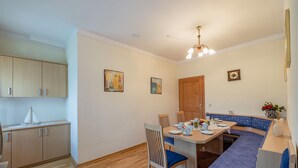 Una cocina compacta con armarios de madera, una mesa de comedor con sillas, un banco empotrado y un pequeño reloj en la pared.