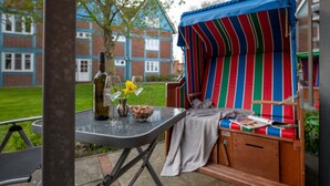 Un patio con una mesa, una zona de estar al aire libre a rayas y un edificio en el fondo.