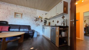 A compact living space with a kitchenette, a sofa, and a dining table.