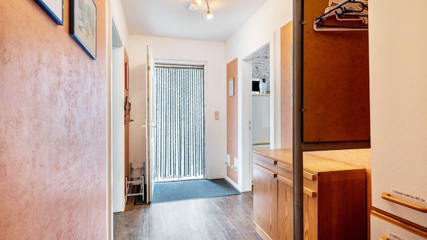 A hallway with a wooden cabinet, a door with a metal handle, and a light fixture.