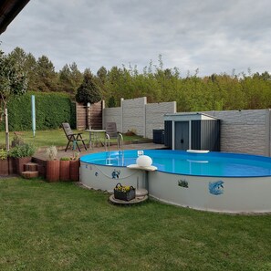 Un patio trasero con piscina, jacuzzi y una zona de estar techada.