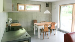 Eine moderne Küche mit einem Edelstahl-Kochfeld, einem Holzespeisetisch mit Stühlen und einem großen Fenster, das für natürliches Licht sorgt.