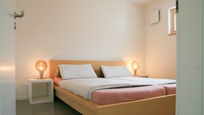 Ein Einzelbett mit Holzrahmen, zwei Nachttische und zwei Wandleuchten.