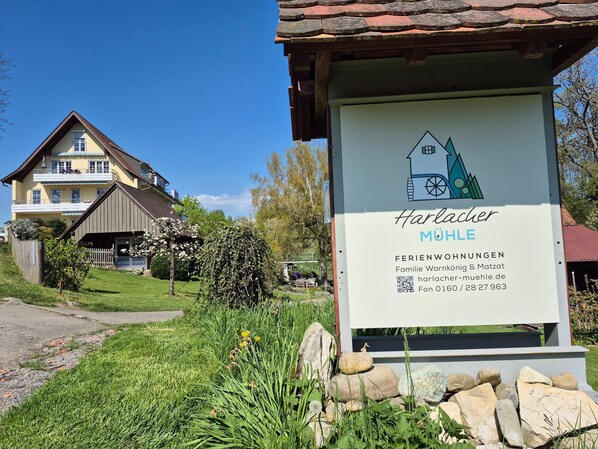 A sign for 'Harlacher Mühle' with a house and mountain graphic, indicating a family-owned and operated lodging.