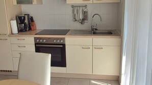 A modern kitchen with a stove, oven, sink, and hanging utensils. - Apartment 2 with Terrace (Stetten)