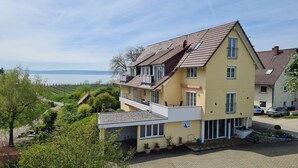 A two-story building with a balcony, a view of the sea, and a paved driveway. - Apartment 2 with Terrace (Stetten)