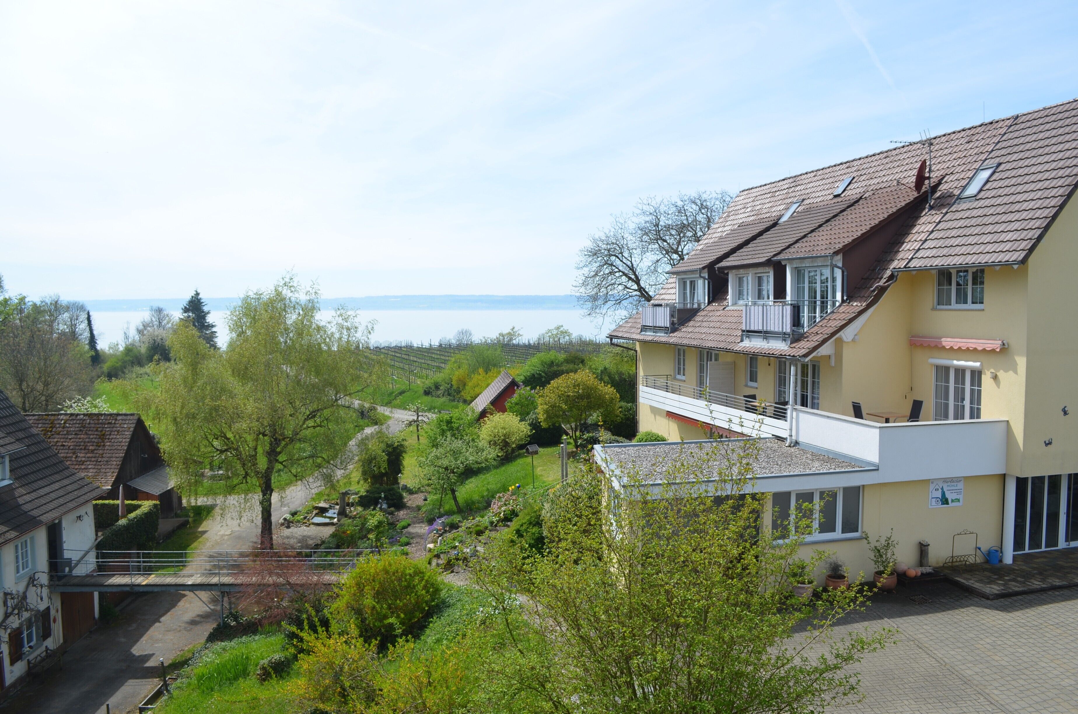 A residential building with a balcony, a view of a body of water, and a garden area.
