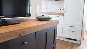 A modern kitchen with a wooden countertop, a black Hisense TV, and white cabinets. - Wilzenberg Holiday Apartment – 62 sqm (Schmallenberg)