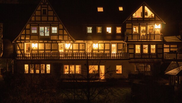 A large, multi-story building with multiple windows and balconies, illuminated at night.