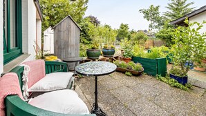 A patio with a green chair, a small round table, and a wooden shed in the background.