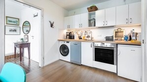 A compact kitchen with a washing machine, oven, and a coffee machine.