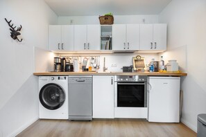 A compact kitchen with a washing machine, dishwasher, oven, and a small refrigerator. - Apartment 'Im Reiterparadies' with Private Terrace, Private Garden and Wi-Fi (Salzhausen)