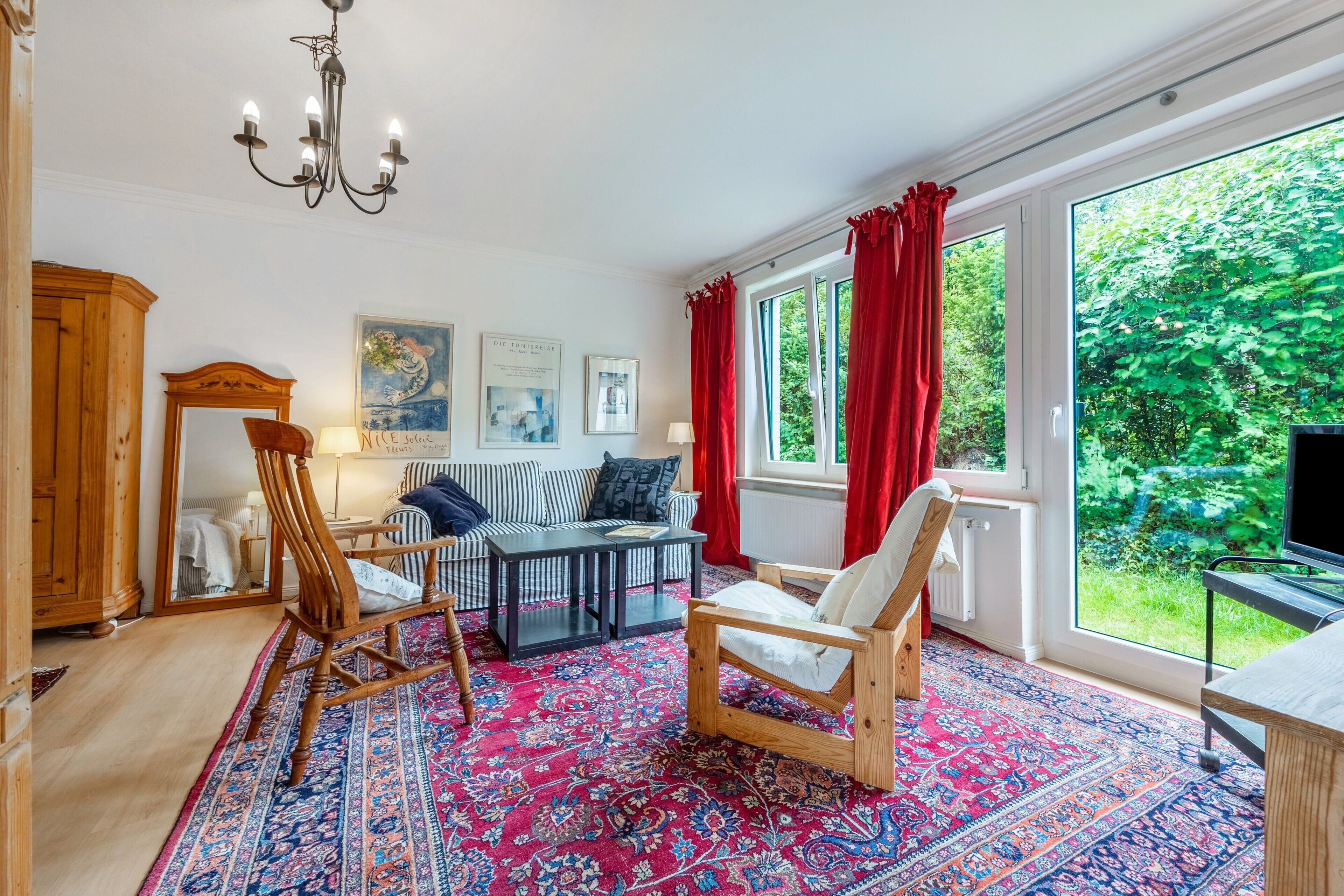 A room with a large window, a wooden chair, a sofa, a table, and a rug.