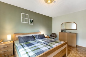 Une chambre à coucher avec un lit en bois, une table de chevet avec une lampe, une armoire et un miroir au mur.