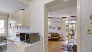 Una cocina compacta con microondas, refrigerador y comedor con mesa y sillas.
