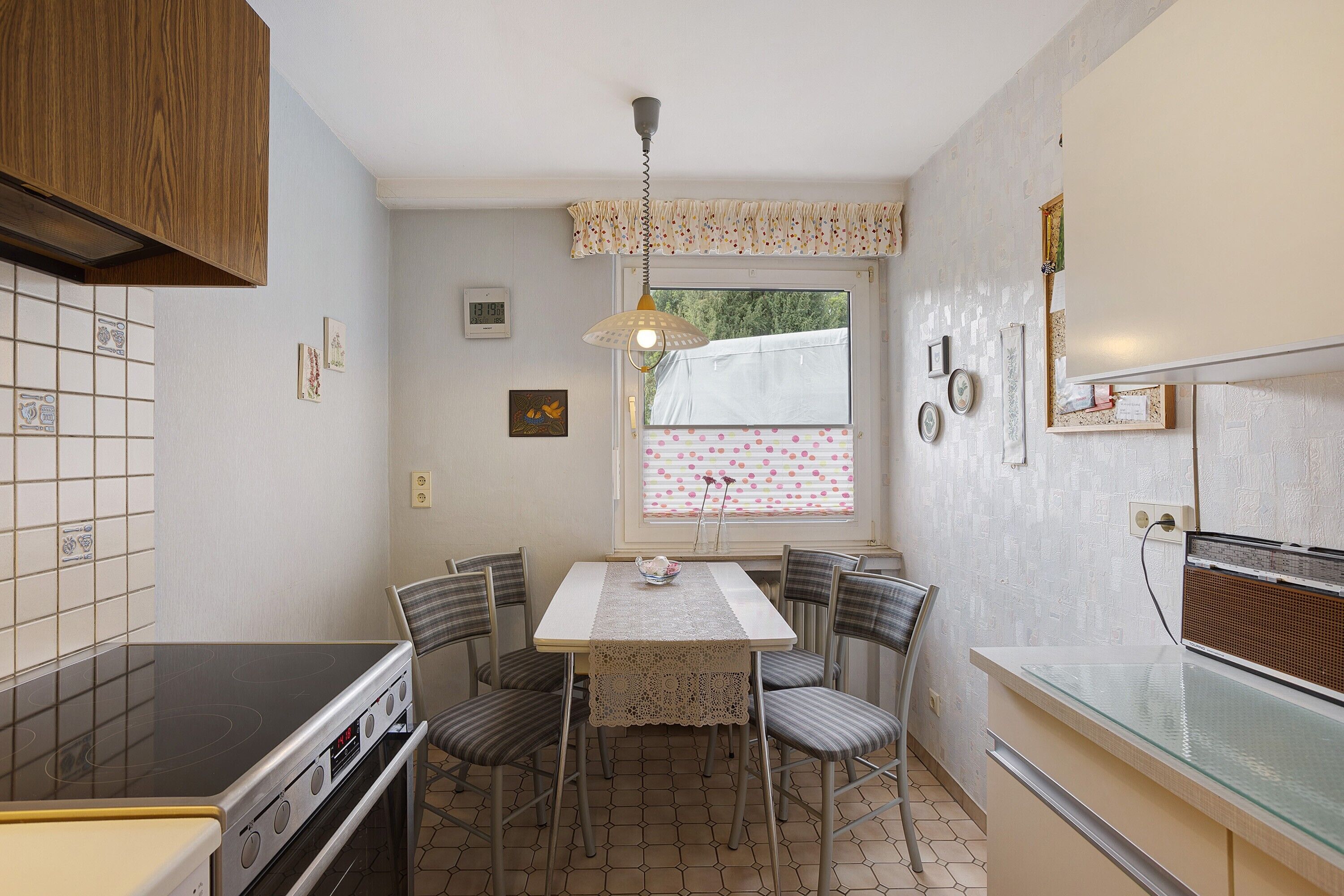 Cocina compacta con estufa, mesa de comedor, sillas y ventana con cortinas.